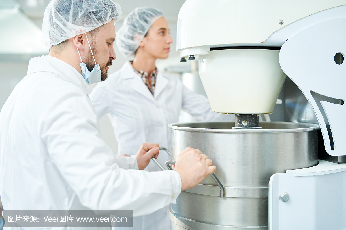 兩個糖果工廠的工人操作機器